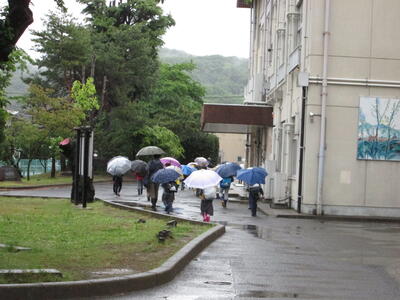 傘をさして登校する子どもたち