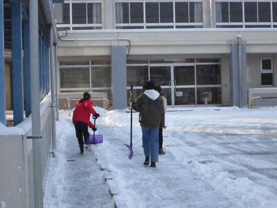 雪かきを手に、校舎南に向かう子どもたちです。