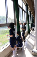 体育館ギャラリーの窓を拭く３年生と保護者